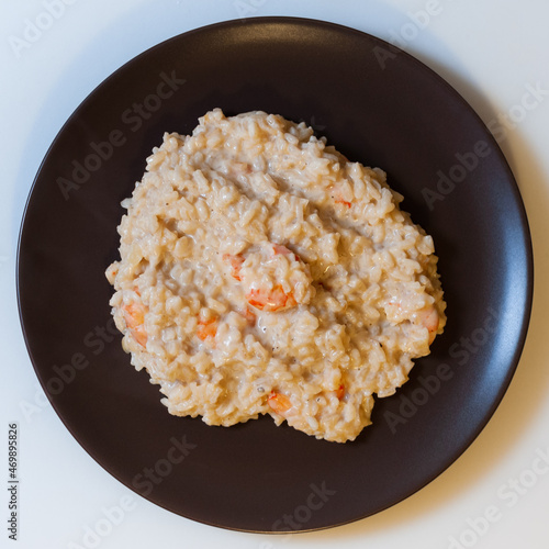Risotto with shrimp in cream sauce on a dark plate