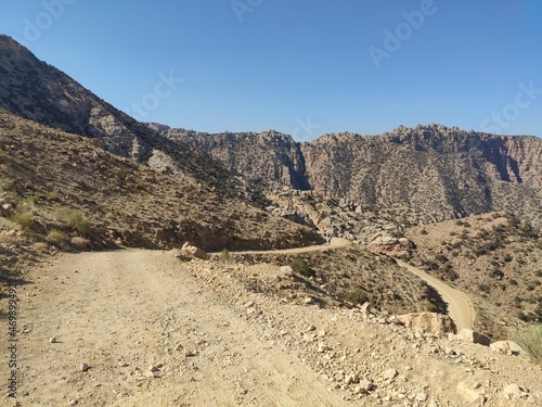 Dana, la plus grande réserve naturelle de Jordanie, marche en plein milieu d'une zone montagneuse rouge et blanche, avec un peu de verdure et de la forte chaleur, sans ombre, chemin de cailloux