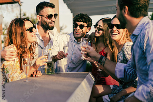 Canvas Print Group of young people having a fun party drinking champagne together standing at