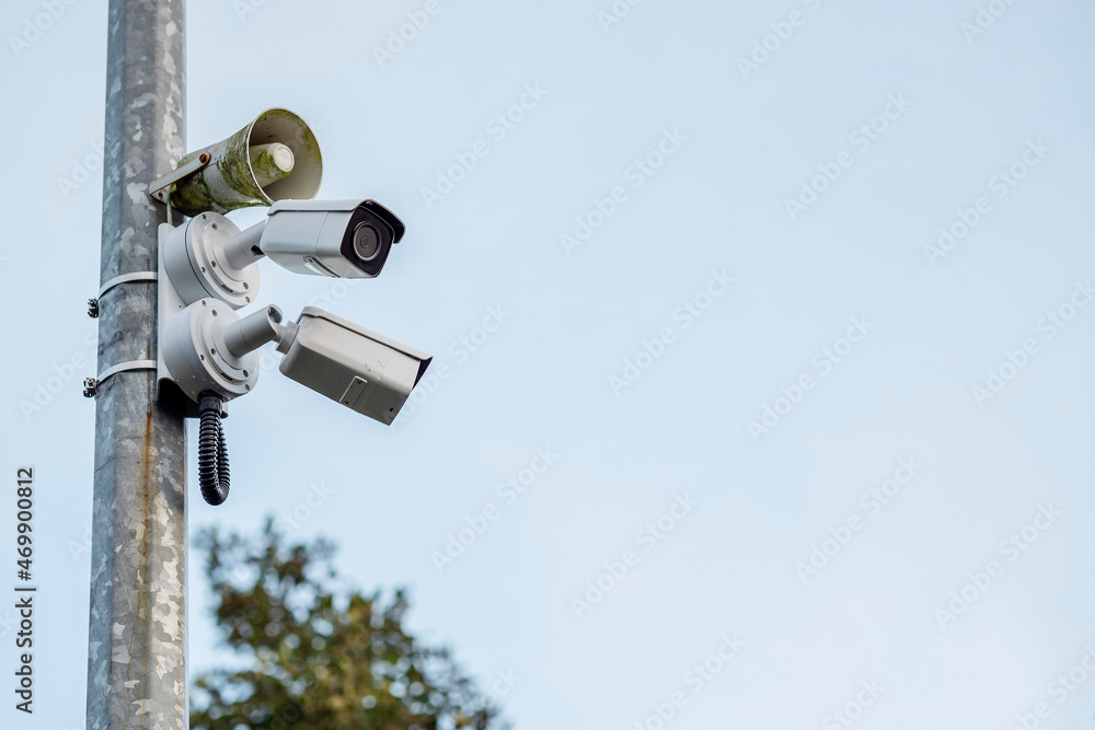 Two security cameras and loudspeaker on a metal post. Safety industry concept. Modern surveillance concept. Two security cameras and loudspeaker on a metal post. Safety industry concept. Modern surveillance concept.