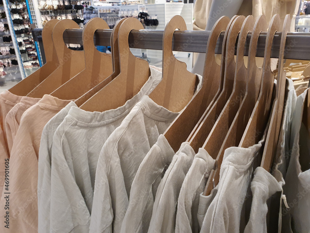 Gender neutral style t-shirts hang on eco-friendly cardboard paper hangers  on rack in casual clothes store in trendy pastel tones and nude colors.  Gender free clothing concept. Selective focus Stock Photo