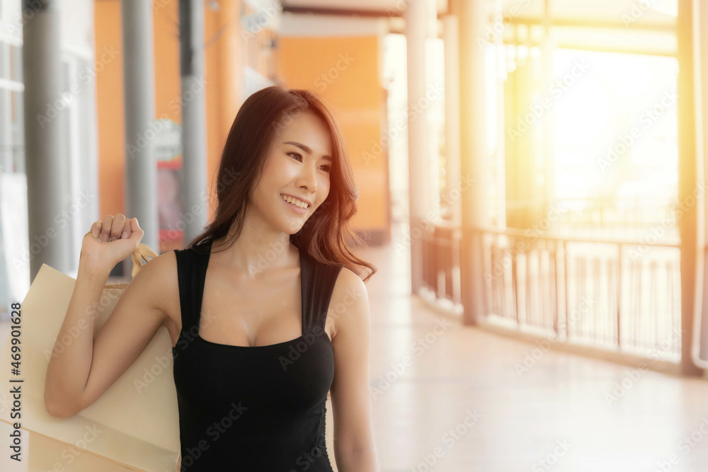 Beautiful young asian woman is carrying shopping bags with shopping bags enjoying in shopping and smiling while doing shopping in the outlet, shopping mall. Beautiful young asian woman is carrying shopping bags with shopping bags enjoying in shopping and smiling while doing shopping in the outlet, shopping mall.