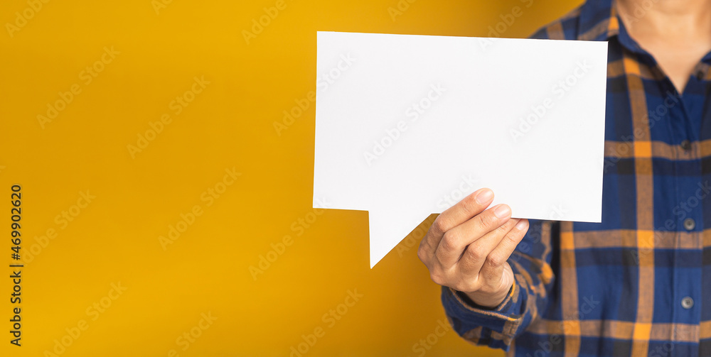 Business and speech bubble concept. Businessman in a blue shirt holding an empty speech bubble paper while standing on a yellow background in the studio. Space for text. Close-up photo Business and speech bubble concept. Businessman in a blue shirt holding an empty speech bubble paper while standing on a yellow background in the studio. Space for text. Close-up photo