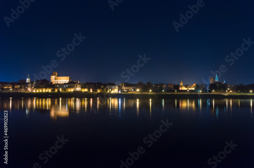 Night view of panoramic view on Old town of Torun city walls and reflection in Vistula river.