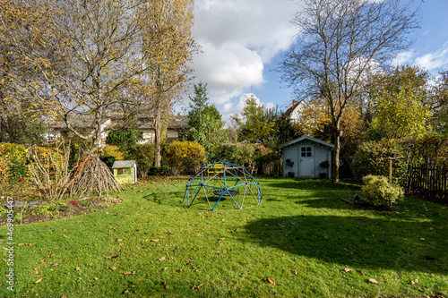 Nice green garden backyard with a little vintage blue garden house and a some children playground items
