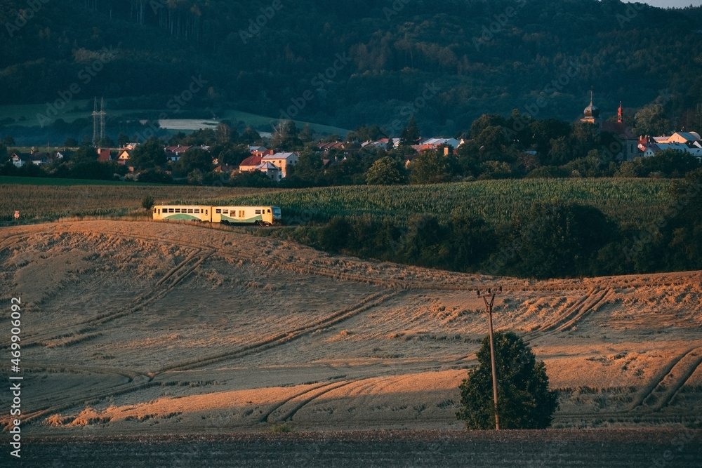 transport passenger train on railway in field with village at background