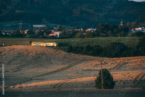 transport passenger train on railway in field with village at background