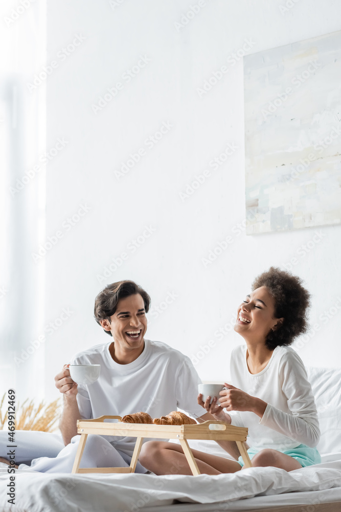 cheerful interracial couple having breakfast in bed cheerful interracial couple having breakfast in bed