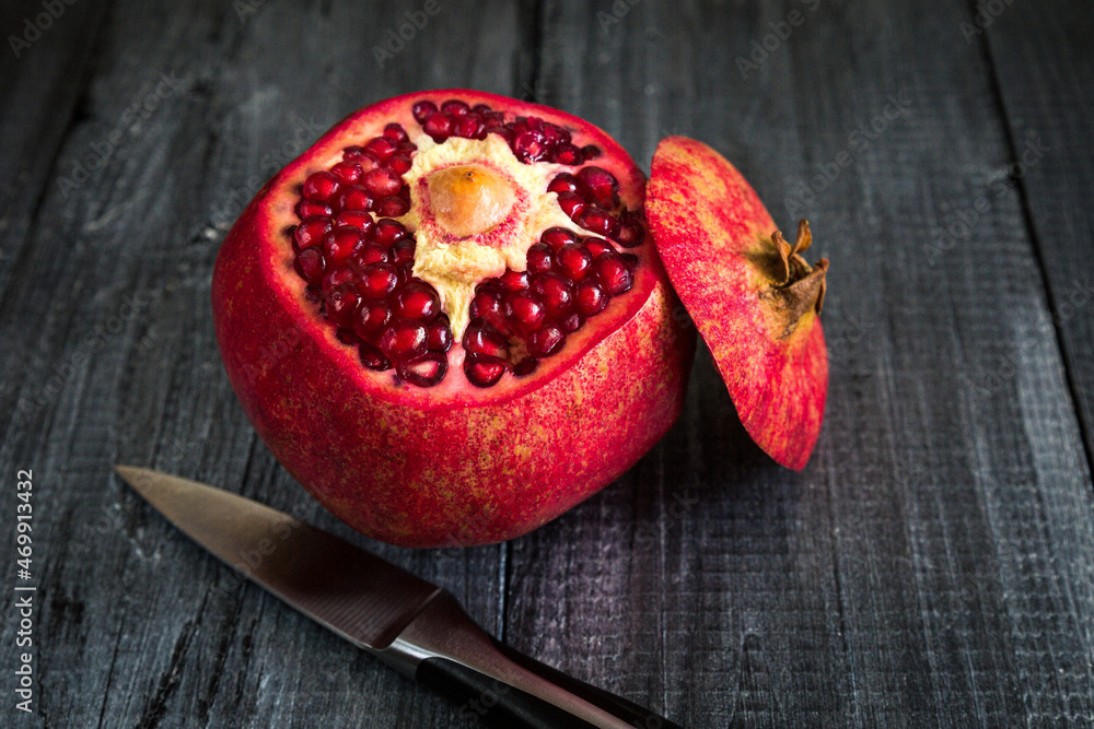 Red ripe pomegranate on a dark wooden background.