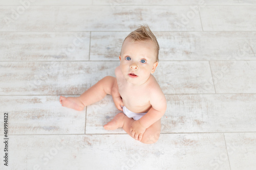 cute baby boy on a white background with a hairstyle and big blue eyes in diapers on a white background with a hairstyle, top view