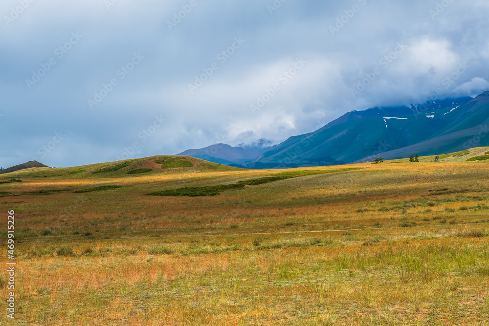 Background of agricultural field and mountains. Autumn wide steppe under a cloudy sky. Sky with mountains in the background.