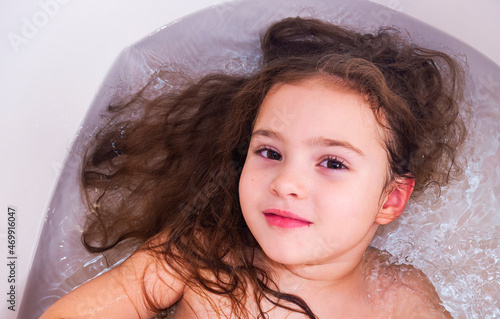 Sweet baby girl in bath. Child girl bathes in a white bathtub.