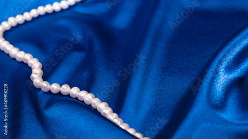 pearl beads on blue luxury satin fabric. Background. elegant wallpaper. Selective focus