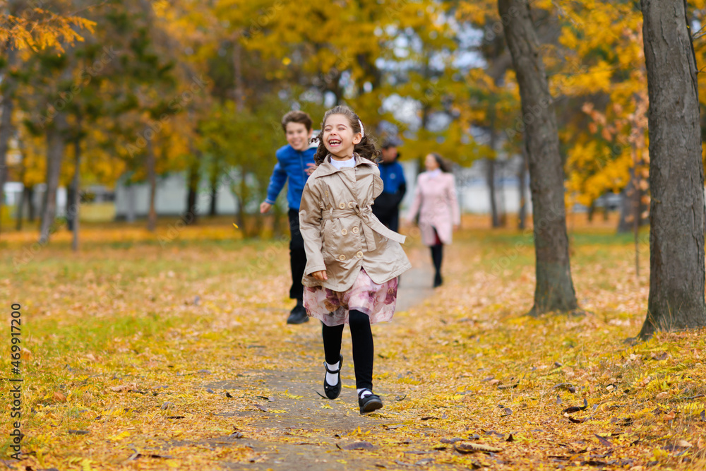 Children run along path in autumn park. They play and laugh, they have a lot of fun. Beautiful nature and trees with yellow leaves. Children run along path in autumn park. They play and laugh, they have a lot of fun. Beautiful nature and trees with yellow leaves.