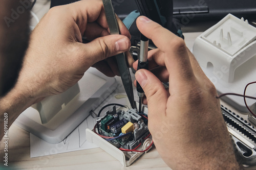 Repair of electronic devices, tin soldering parts. Hands of man holding screwdriver. Computer circuit board