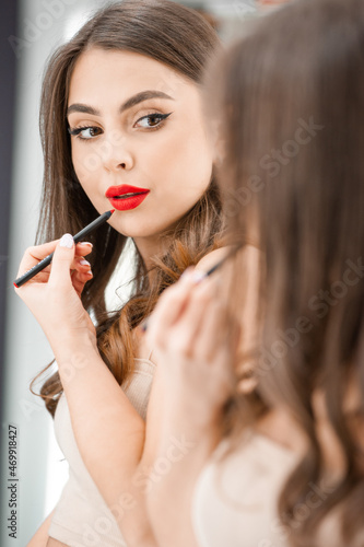Makeup artist applies lips pencil . Beautiful woman face. Hand of visagiste, painting cosmetics of young beauty model girl . Make up in process