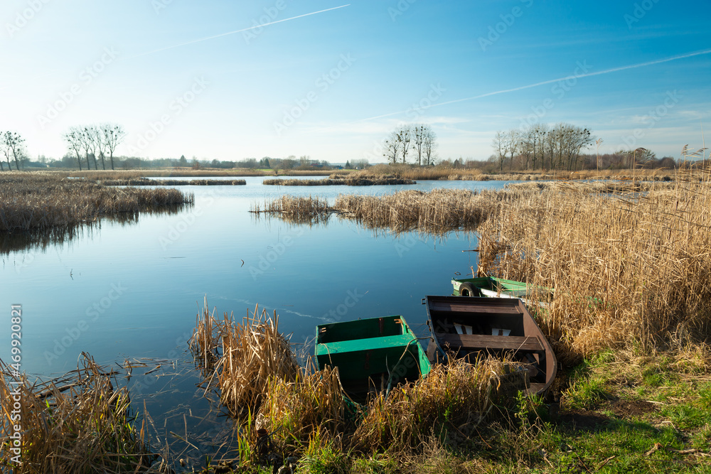 Fototapeta premium Anglers' boats on the shore of a calm lake