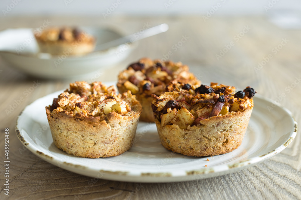 Horizontal close-up of little home-made apple pies with pieces of apple and raisins on a porcelain plate. Selective focus and copy space Horizontal close-up of little home-made apple pies with pieces of apple and raisins on a porcelain plate. Selective focus and copy space