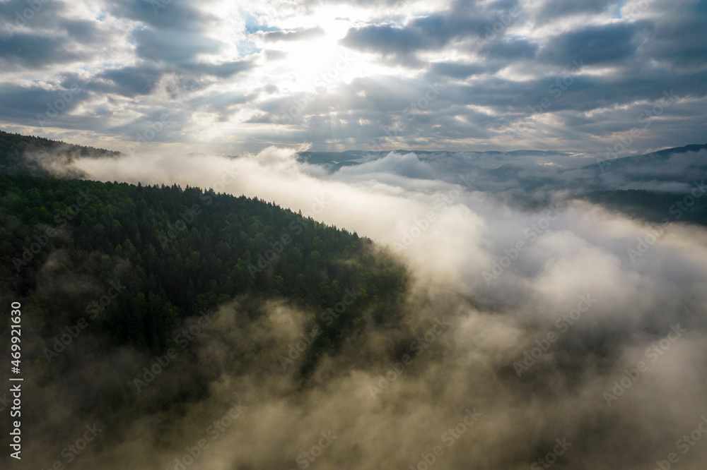 Flying over the clouds during morning sunrise in Carpathian Mountains. Above.Golden fluffy clouds moving softly on the sky and the sun shining through the clouds with beautiful rays and lens flare.