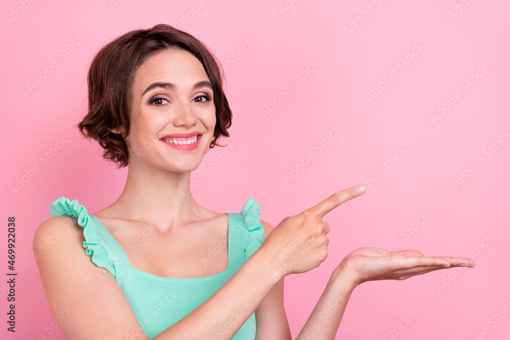 Photo of adorable sweet young lady wear teal singlet holding arm pointing finger empty space isolated pink color background Photo of adorable sweet young lady wear teal singlet holding arm pointing finger empty space isolated pink color background