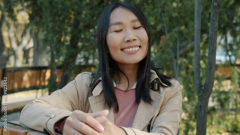 Slow motion portrait of joyful Asian business lady smiling outdoors against autumn trees background in city park. Emotions and expressions background. Slow motion portrait of joyful Asian business lady smiling outdoors against autumn trees background in city park. Emotions and expressions background.