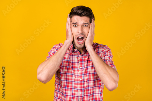 Portrait of attractive amazed worried overwhelmed guy sudden news reaction isolated over bright yellow color background photo