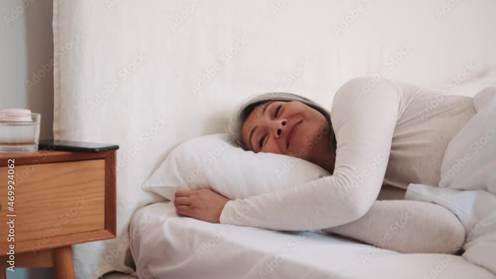 Laughing Asian woman wake up and looking at the phone in the bed Laughing Asian woman wake up and looking at the phone in the bed