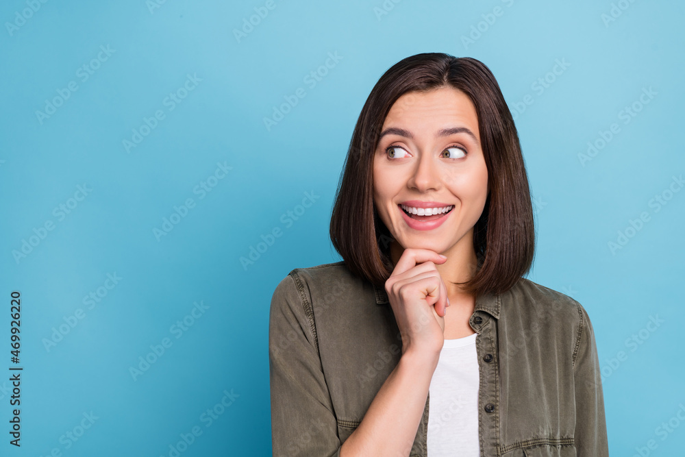 Photo of impressed lady look empty space touch hand chin think thoughts wear khaki clothes isolated over blue color background Photo of impressed lady look empty space touch hand chin think thoughts wear khaki clothes isolated over blue color background