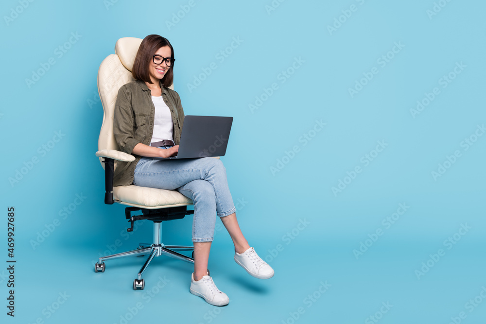 Full body photo of manager ceo lady sit chair use device netbook online communicate wear jeans isolated over blue color background Full body photo of manager ceo lady sit chair use device netbook online communicate wear jeans isolated over blue color background