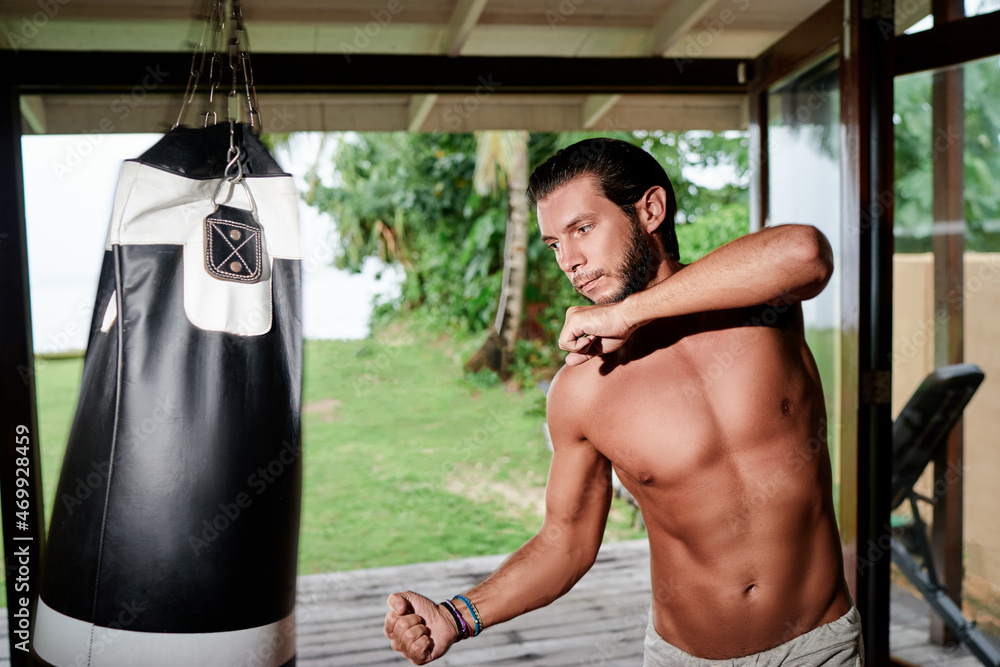 Male boxer hitting a huge punching bag at a gym. Man boxer training hard.