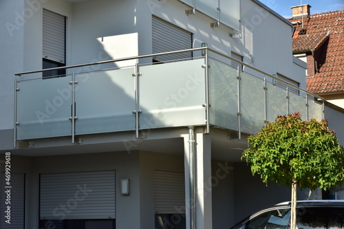 Balkon mit Edelstahl-Geländer und Sichtschutz aus Milchglasplatten an der Fassade eines modernen Mehrfamilien-Wohnhauses