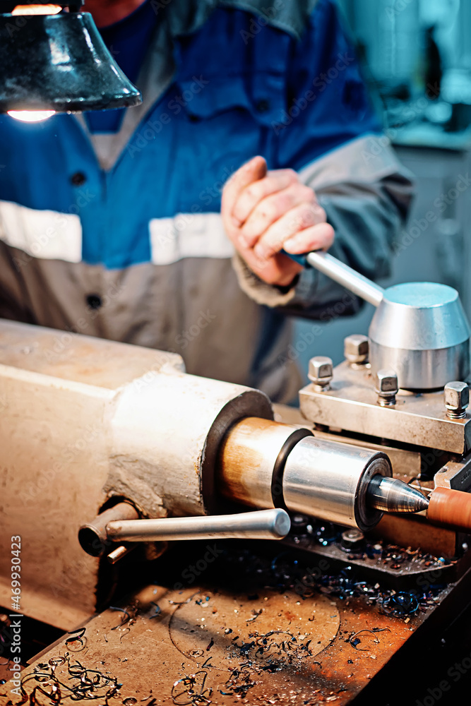 Turner's hands and lathe close-up. Turner works at workplace in lathe shop. Industrial background. Turner's hands and lathe close-up. Turner works at workplace in lathe shop. Industrial background.