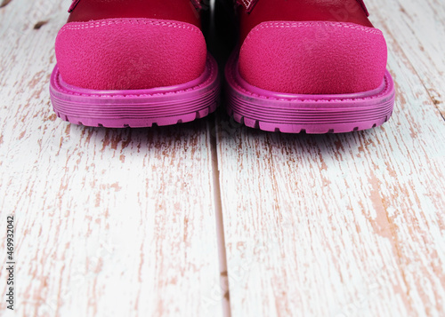 red leather children's boots on a wooden background, a copy of the space
