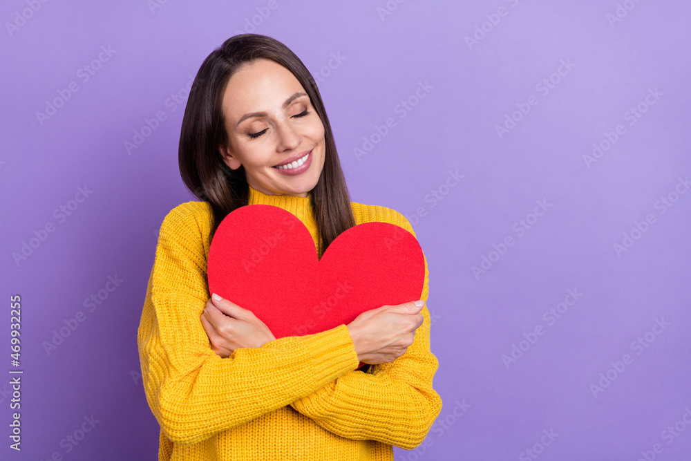 Photo of nice brunette young lady hug heart wear yellow pullover isolated on violet color background Photo of nice brunette young lady hug heart wear yellow pullover isolated on violet color background