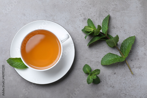 Cup of hot aromatic mint tea on light grey table, flat lay