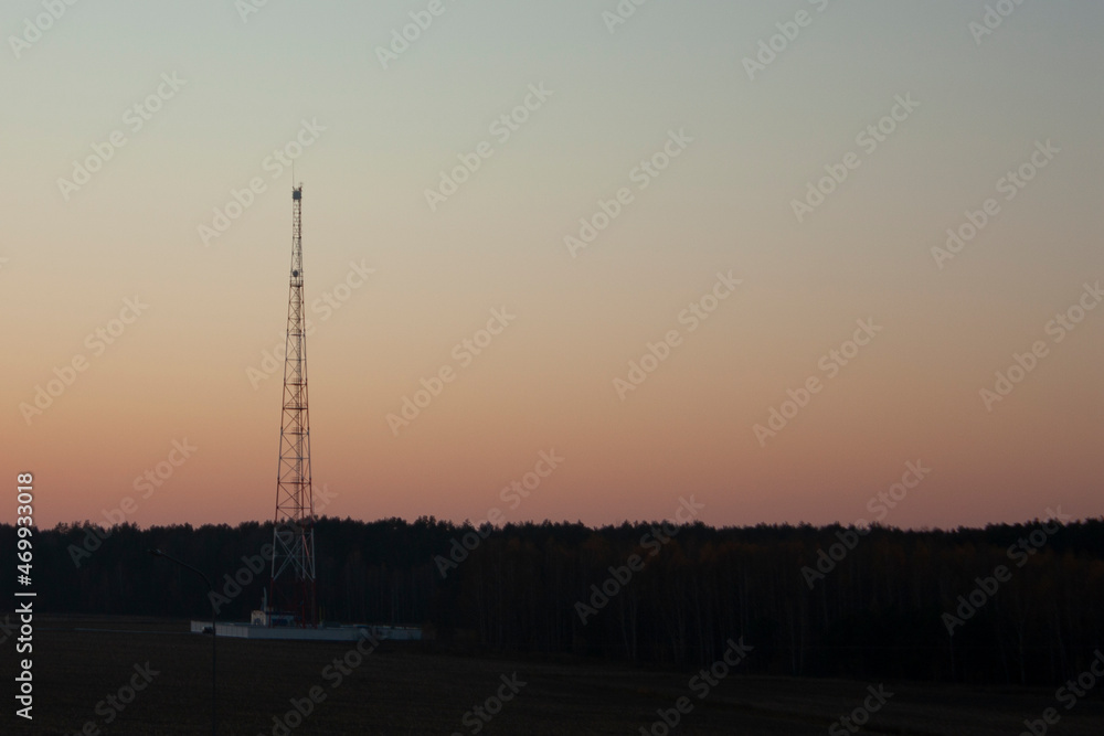Communication tower on the background of sunset and clear sky. Telecommunications equipment against the background of the evening sky.
