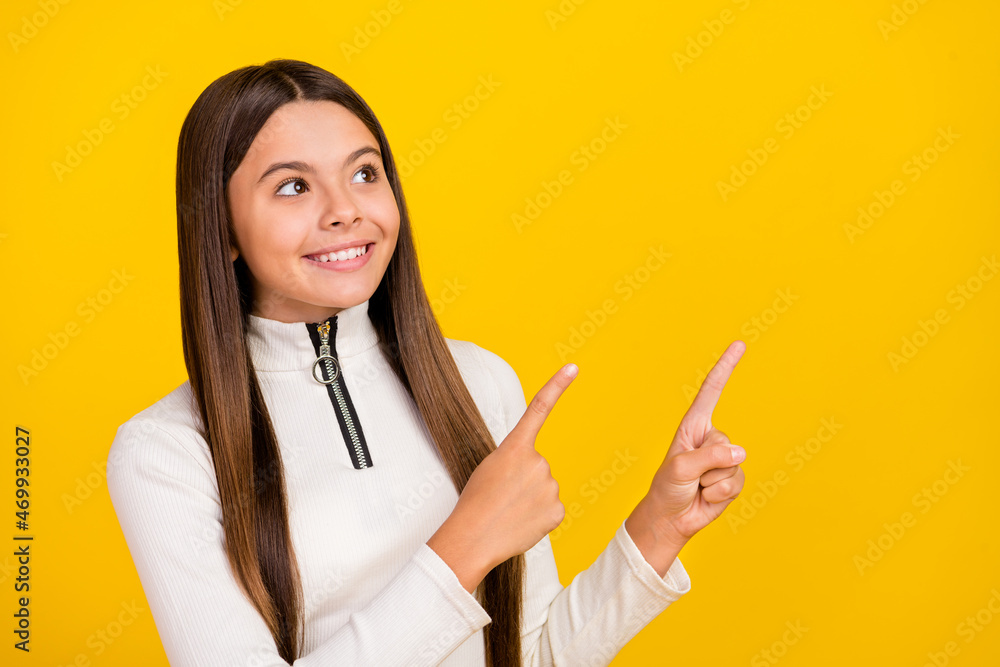 Photo of adorable thoughtful preteen girl dressed white zipper shirt pointing looking two fingers empty space isolated yellow color background Photo of adorable thoughtful preteen girl dressed white zipper shirt pointing looking two fingers empty space isolated yellow color background