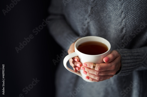 Cozy home. Female hands holding hot cup of coffee or tea.