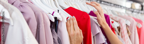 partial view of woman choosing clothing in boutique, banner photo
