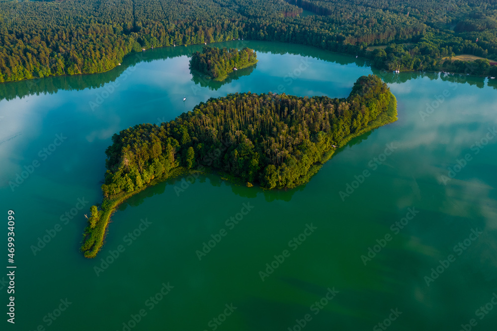 Bird's eye view of the green island in the middle of the lake in a daylight. Bird's eye view of the green island in the middle of the lake in a daylight.