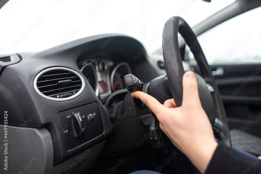 car driver hand push the button and activate windscreen wipers