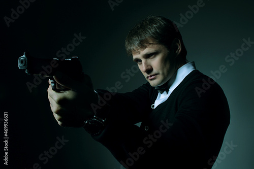 Male portrait in the dark with a gun in his hand