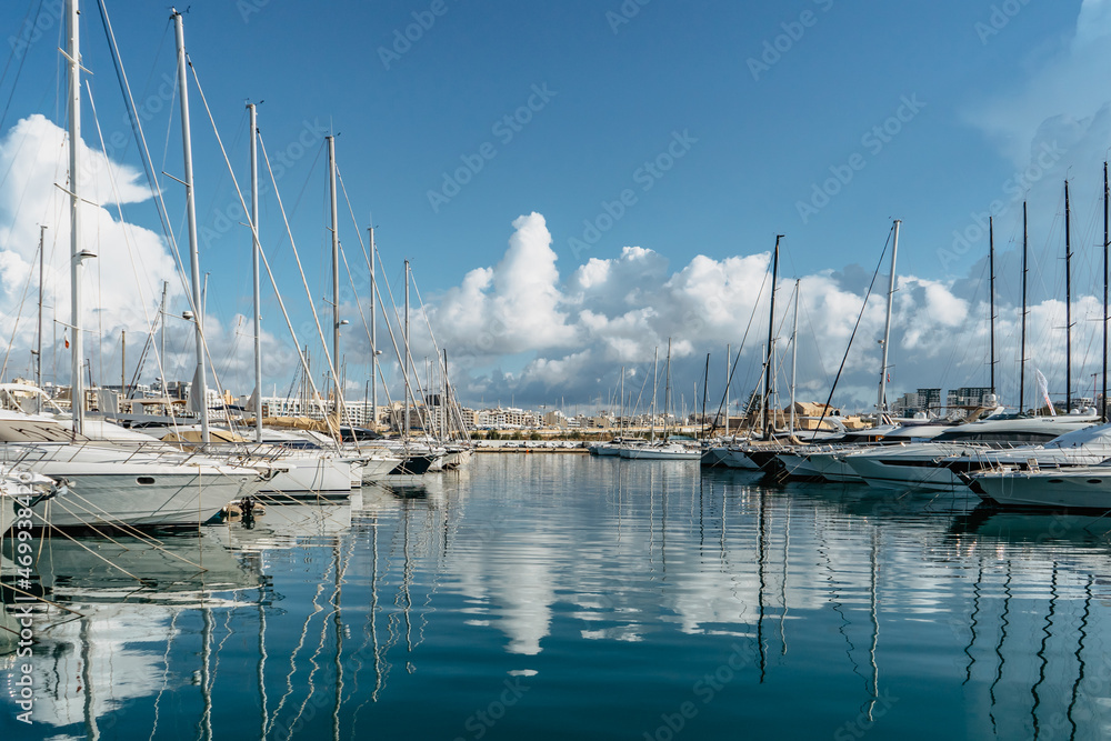 Luxury boats and yachts in harbor. Sunny summer day.Holiday high class lifestyle travel concept.Boat trip in Mediterranean.View of expensive sailing yachts at pier with water reflection.Marine dock