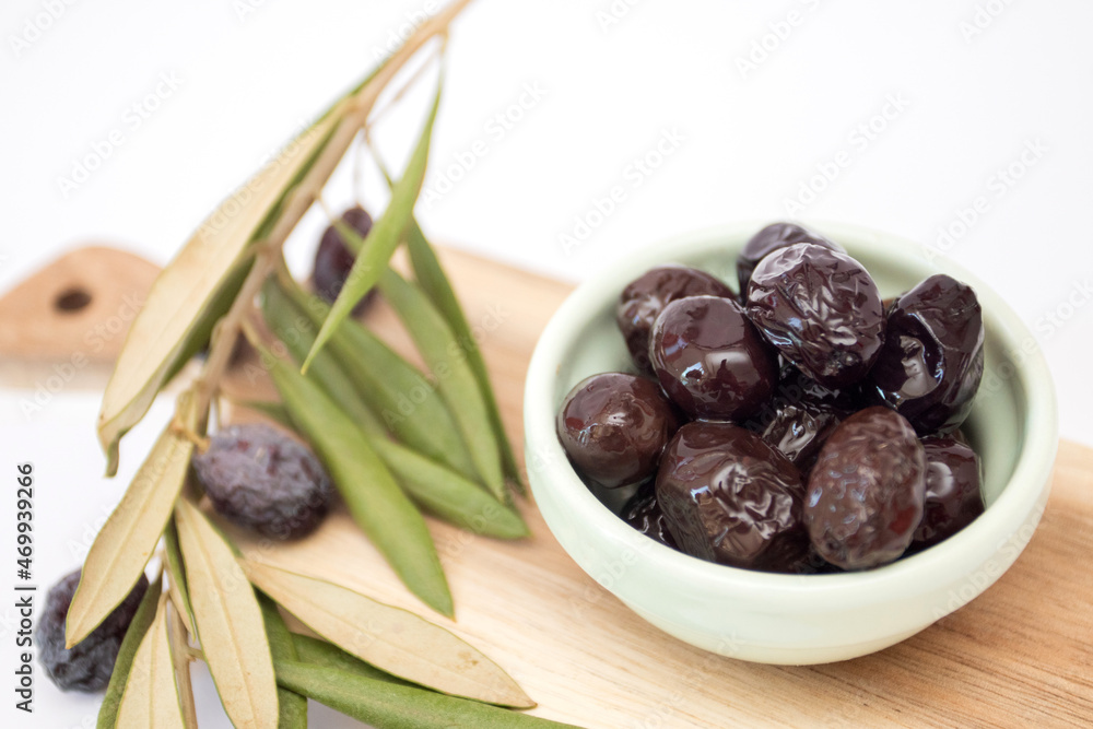 Black olives in a bowl with a branch of an olive tree Black olives in a bowl with a branch of an olive tree