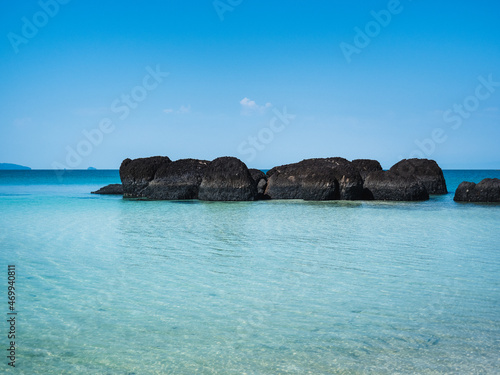Peaceful white sand beach with iconic black volcanic rock of Koh Kham Island and crystal clear turquoise water. Near Koh Mak Island, Trat Province, Thailand.
