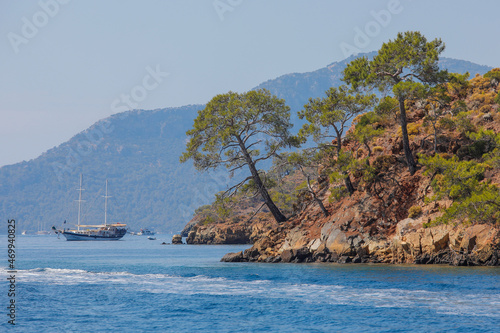 Blue sea, boat and coast with stones and trees