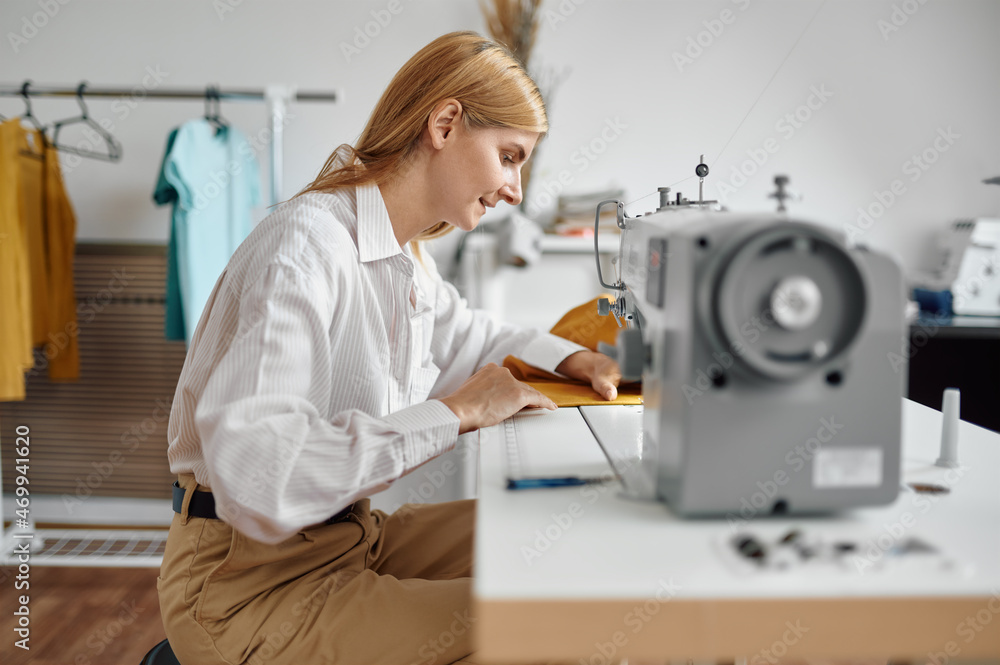 Dressmaker sews cloth on sewing machine, workshop Dressmaker sews cloth on sewing machine, workshop