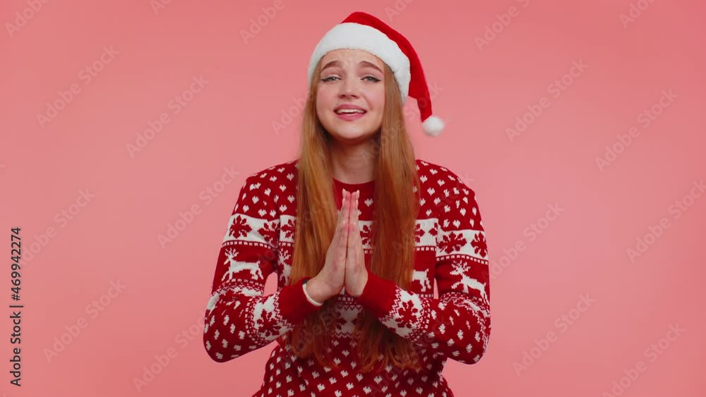 Girl in Christmas Santa sweater praying, looking upward, making wish, asking with hopeful imploring expression, begging apology isolated on pink studio background. Happy New Year celebration holiday Girl in Christmas Santa sweater praying, looking upward, making wish, asking with hopeful imploring expression, begging apology isolated on pink studio background. Happy New Year celebration holiday