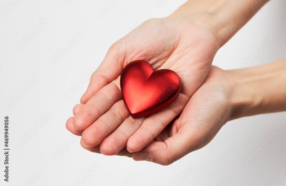 Hands holding red heart, close-up, white background Hands holding red heart, close-up, white background