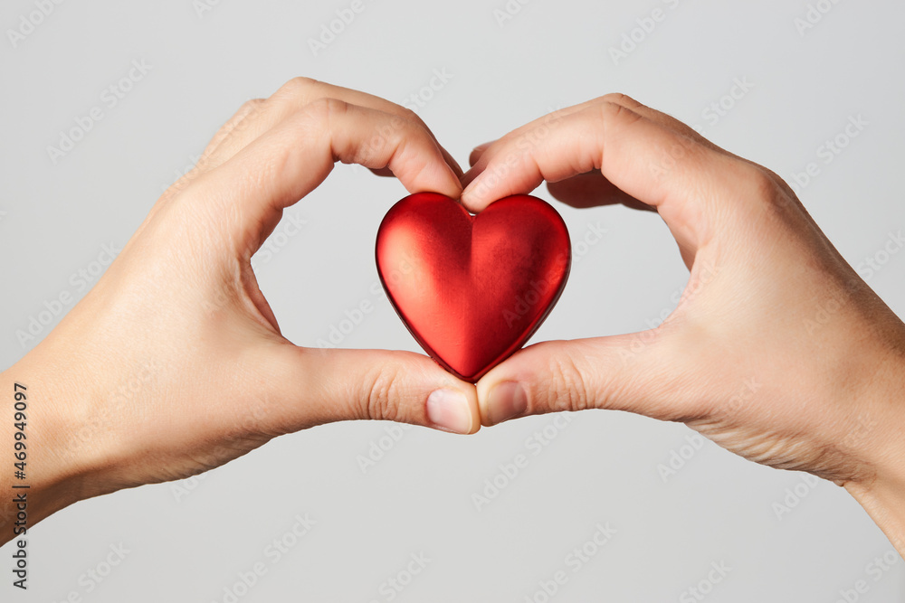 Fototapeta premium Hands holding red heart, close-up, white background